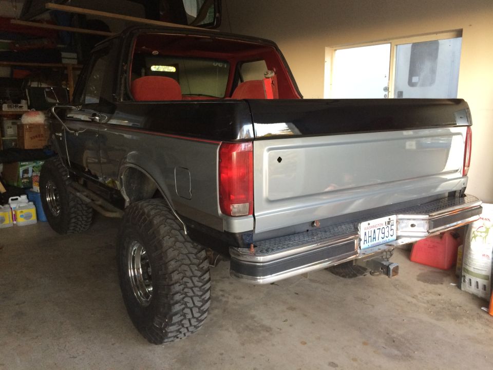 Gray and black Ford Bronco with lifted suspension and off-road tires, viewed from the rear