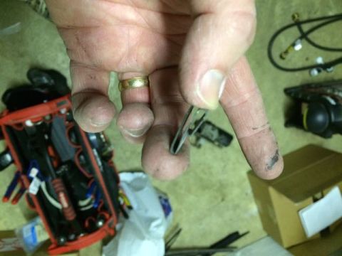 1990 Ford F-150 - A hand, wearing a gold ring, holds a metal clip over a red toolbox and other workshop items.