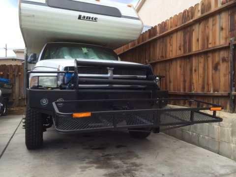 1997 Dodge 3500 - A white 1994 Dodge Ram truck with a Lance camper and a front hitch rack is parked in front of a wooden fence.
