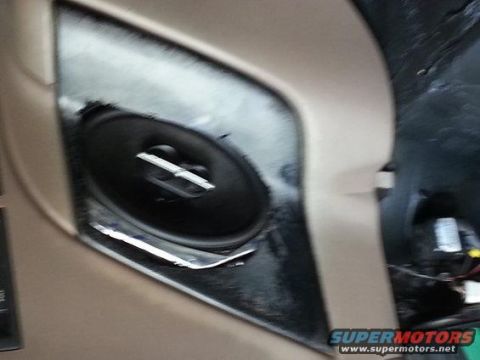 1994 Ford Bronco - Photograph of an oval car speaker mounted in a tan door panel, not a technical document.