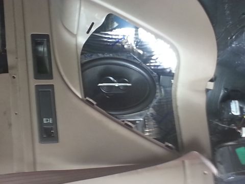 1994 Ford Bronco - Photograph of a tan vehicle door panel with a speaker and sound deadening installed, not a document.