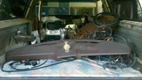 1982 Ford Bronco - The interior of a vehicle is packed with car parts, including a dashboard, steering wheel, and a large bundle of wiring. A small hula dance…