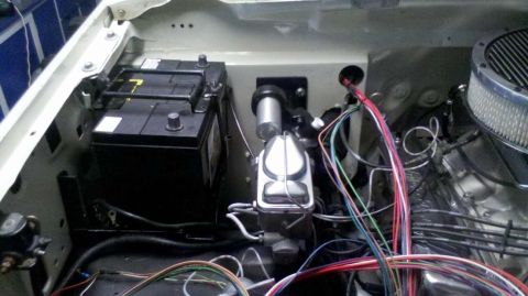 1982 Ford Bronco - The engine bay of a classic vehicle, likely a 1982 Ford Bronco, shows a black battery, brake master cylinder, and a portion of the engine w…