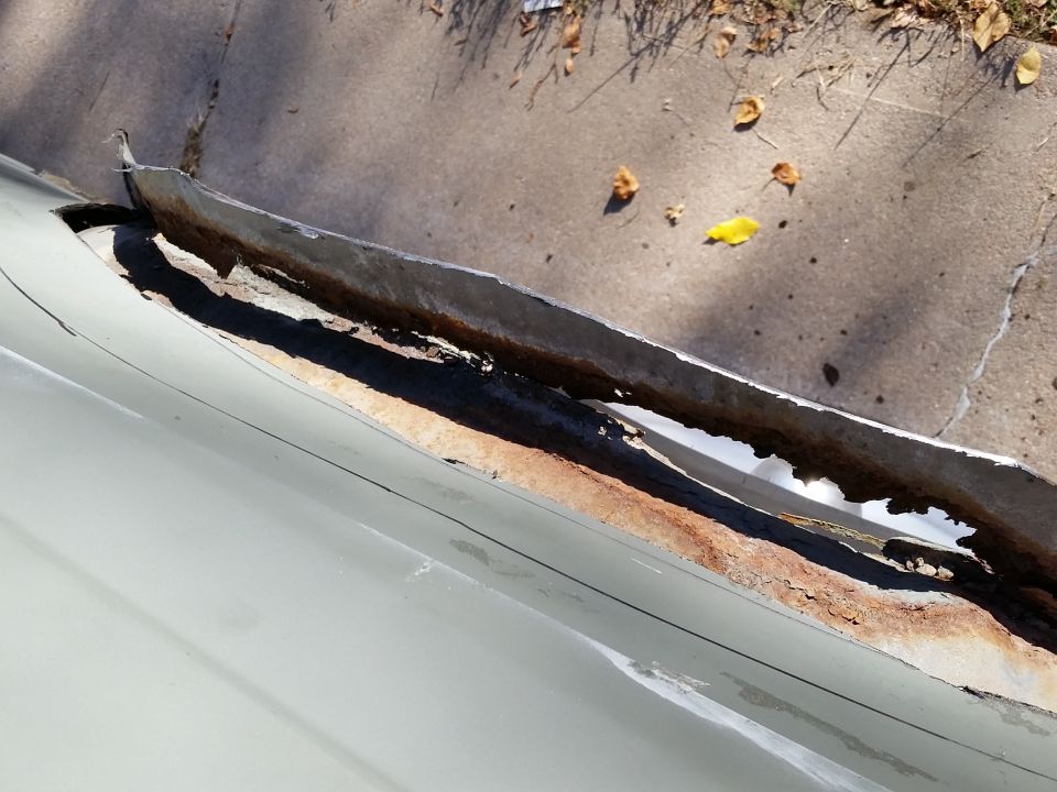 Close-up of rusted and peeling metal trim on a vehicle.
