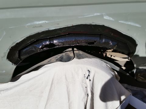 1988 Ford Bronco - A close-up view shows a section of a vehicle's body that has been cut out and painted black, revealing rust and damage underneath. A white…