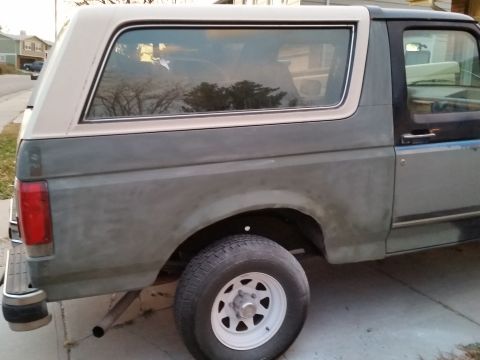 1988 Ford Bronco - The rear passenger side of a two-tone Ford Bronco is shown, with the upper portion appearing to be tan and the lower portion a faded gray.…