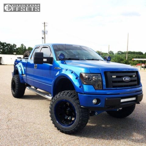 1994 Ford Bronco - A lifted, bright blue Ford F-150 pickup truck with aftermarket fenders and large black wheels is parked on a paved lot.