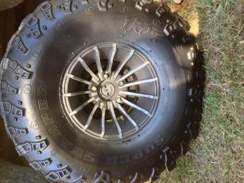 1979 Ford Bronco - A close-up view of a Super Swamper tire mounted on a custom wheel, with grass visible to the side.
