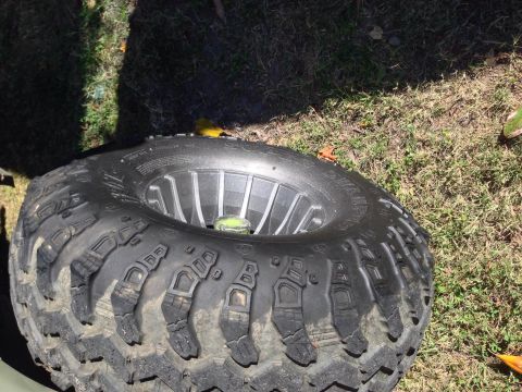 1979 Ford Bronco - Close-up of an off-road tire and wheel assembly lying on the ground.