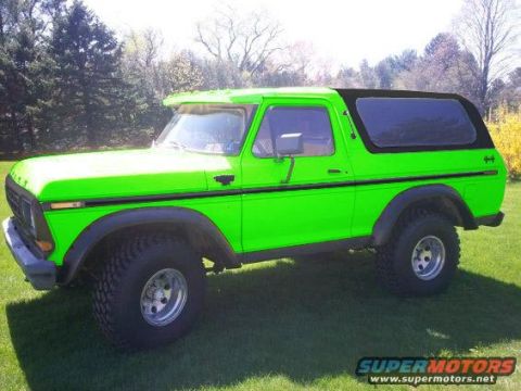 1994 Ford Bronco - A bright green Ford Bronco is parked on a grassy lawn with trees in the background. The vehicle has a black soft top and chrome wheels.