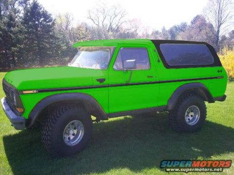 1994 Ford Bronco - A bright green Ford Bronco is parked on a grassy lawn with trees in the background. The vehicle has a black soft top and chrome wheels.