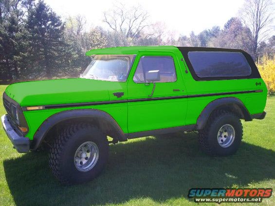 Green Ford Bronco with black soft top and chrome wheels parked on grass.