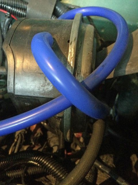 1990 Ford Bronco - A close-up view shows a blue silicone hose routed around a metallic component, likely part of an engine bay. Several other hoses and wiring…