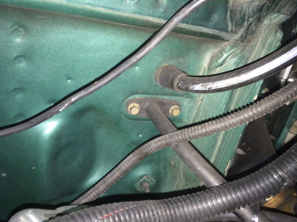 Green vehicle firewall with wires, hoses, and bolts.