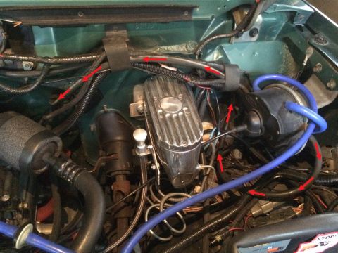 1990 Ford Bronco - A close-up view of the engine bay of a 1990 Ford Bronco, showing various hoses, wiring, and engine components. Red arrows highlight specifi…