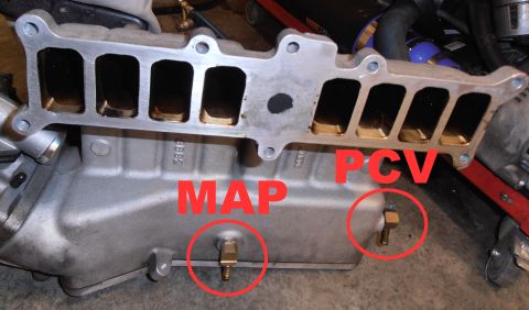 1990 Ford Bronco - A close-up view of an aluminum intake manifold with two brass fittings labeled "MAP" and "PCV", both circled in red. The manifold has multi…