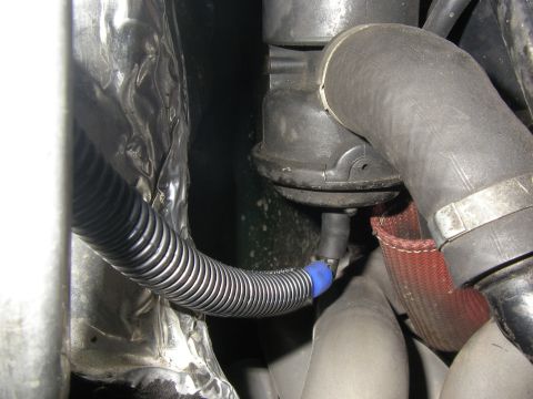 1990 Ford Bronco - A close-up view shows a corrugated black hose with a blue connector, running alongside a silver heat shield and connected to a black compon…