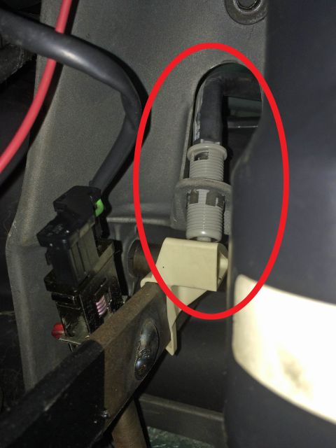 1990 Ford Bronco - A close-up view shows a black cable with a gray threaded fitting passing through a plastic bracket. The cable appears to be part of the veh…