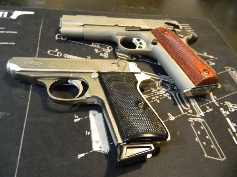 1979 Ford Bronco - Two handguns are displayed on a black mat with schematic diagrams of firearm components. The handgun in the foreground is a silver Walther…