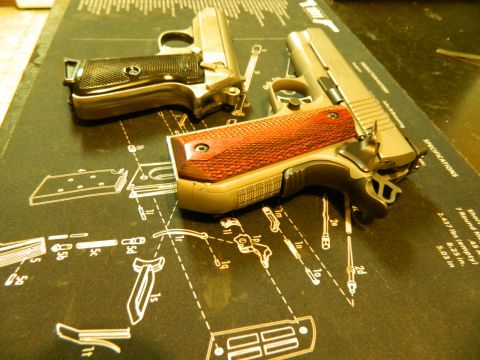 1979 Ford Bronco - Two handguns are laid out on a black mat with diagrams of gun parts. One handgun is silver with a black grip, and the other is tan with a r…