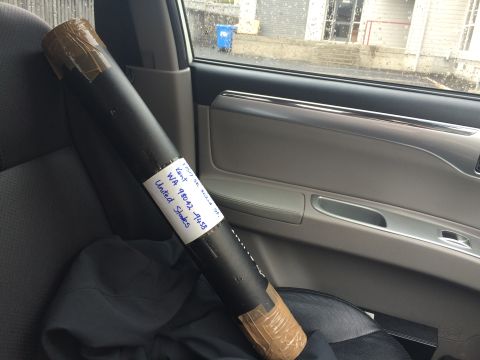 1993 Mazda MX-3 - A rolled document with a shipping label is placed on the passenger seat of a vehicle.