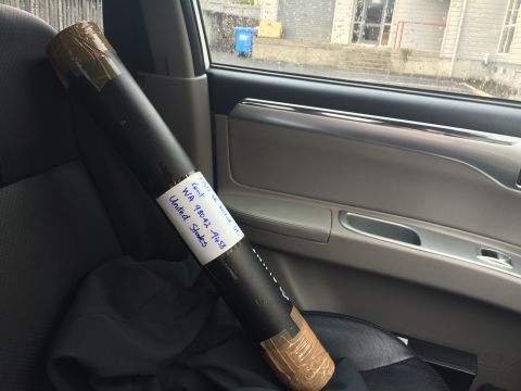 1993 Mazda MX-3 - A rolled document in a tube is secured inside a vehicle, with a shipping label visible on its side.