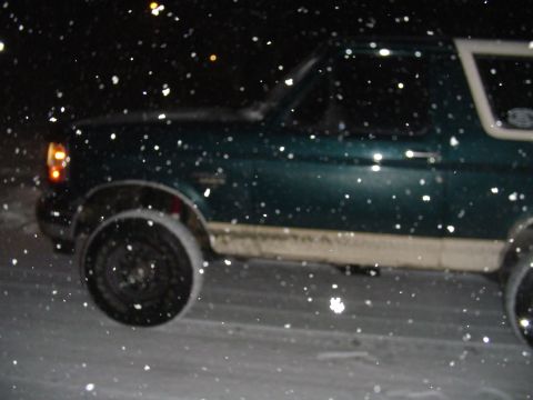 1993 Ford Bronco - A dark green Ford Bronco is seen from the side during a snowfall at night.