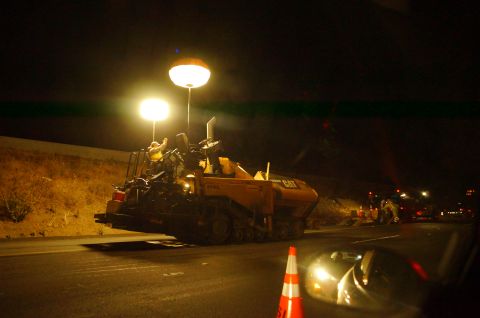 2003 Ford Taurus - Construction scene at night with an asphalt paver and traffic cones on the road.