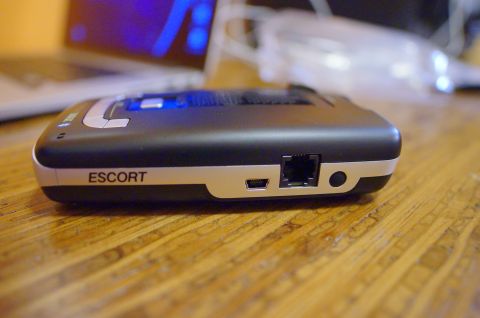 2003 Ford Taurus - Escort radar detector shown on a wooden table, with a laptop in the background.