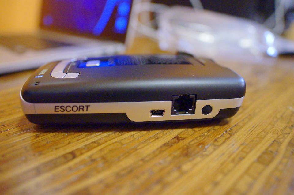 Escort radar detector with USB and RJ11 ports on a wooden surface