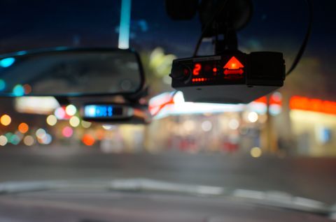 2003 Ford Taurus - Interior view of a radar detector and rearview mirror with blurred background lights.