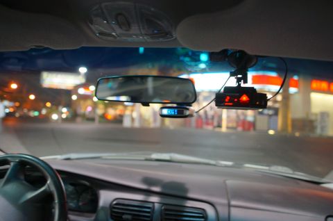 2003 Ford Taurus - A radar detector is mounted on the windshield of a car at night, with the road and lights visible outside.