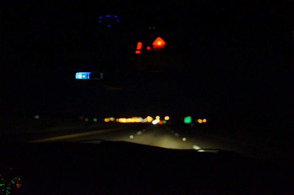Interior view at night, showing dashboard lights and road ahead