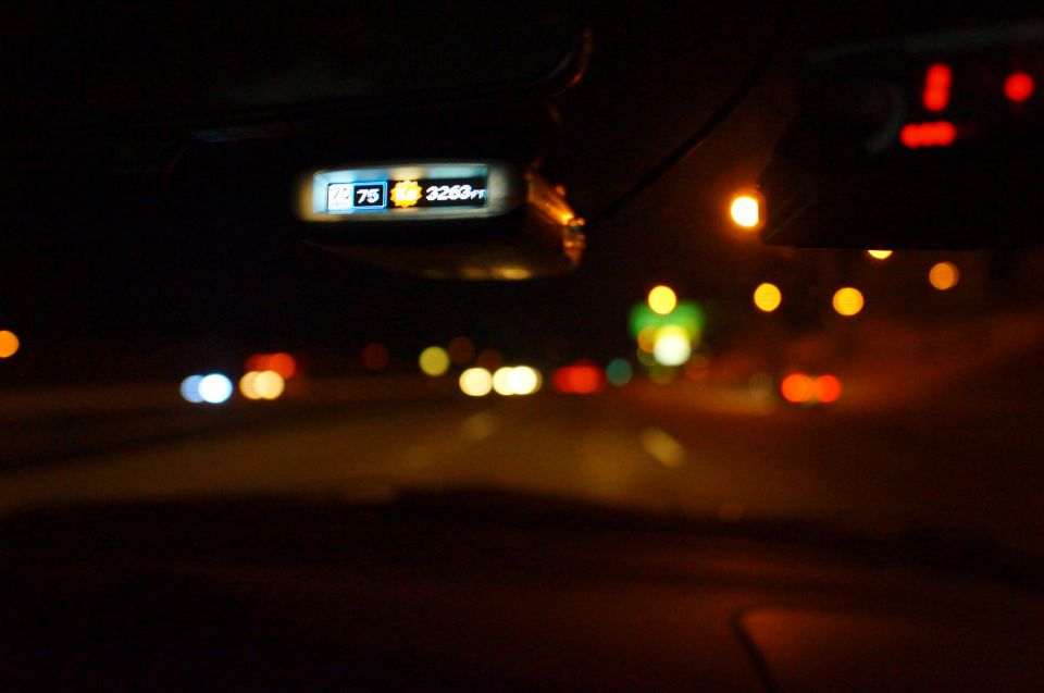 Dashboard display shows 75 degrees and 3263 ft. Highway traffic at night is blurred