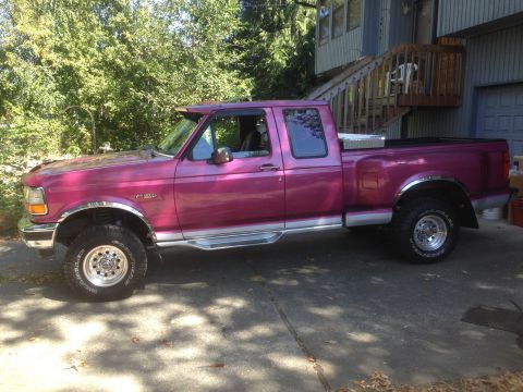 1992 Ford F-150 - A pink 1992 Ford F-150 pickup truck is parked on a driveway, showing its side profile.