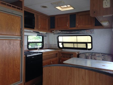 1988 Ford F-350 - The interior of an RV shows a kitchen area with a stove and sink, adjacent to a dinette area.