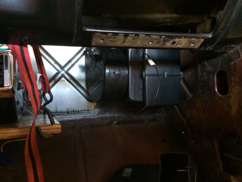 1964 Ford Fairlane - The interior of a vehicle shows a red seatbelt, HVAC unit, and exposed metal bracing under the dashboard.