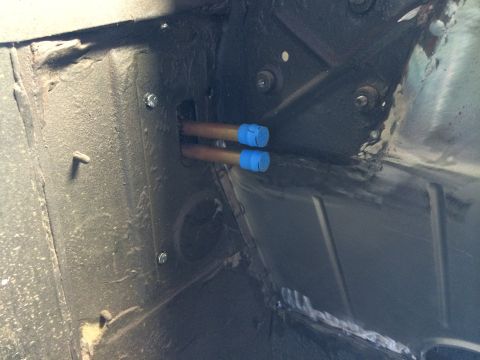 1964 Ford Fairlane - Close-up view of two copper lines, capped with blue tape, within a vehicle's chassis or undercarriage.