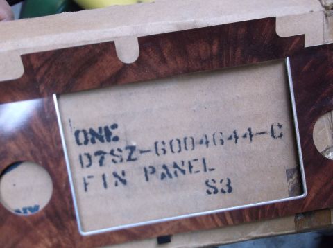 1979 Ford Ranchero - Close-up of a woodgrain trim panel, likely for a vehicle interior, with a visible part number stamped on the backing.