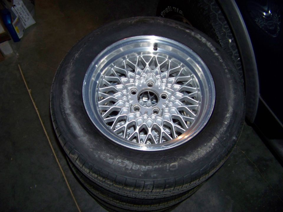 stack of tires with a shiny mesh-style aftermarket wheel on top