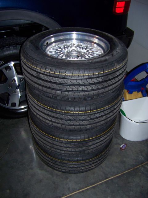 1999 Mercury Grand Marquis - A stack of tires sits on a garage floor next to a dark vehicle.