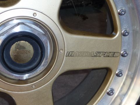 1993 Mazda MX-3 - Close-up of a gold Mazdaspeed wheel a RAYS center cap and visible lug nuts.