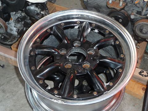 1993 Mazda MX-3 - A black car wheel with a polished lip is shown, with rust visible on the lug nut seats.