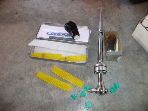 1993 Mazda MX-3 - A short shifter assembly and a separate shift knob are laid out on a concrete floor with packaging materials.