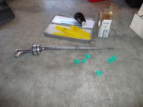 1993 Mazda MX-3 - A collection of automotive parts, including a short shifter, shift knob, and bushings, laid out on a concrete surface.