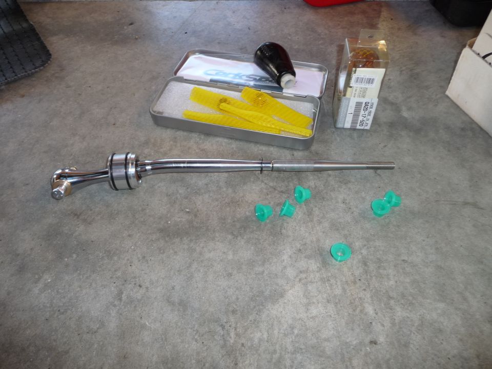 Chrome short shifter with green plastic bushings and a black shift knob in a tin
