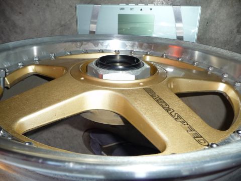 1993 Mazda MX-3 - A gold Mazdaspeed wheel is shown on a digital scale, suggesting it is being weighed.