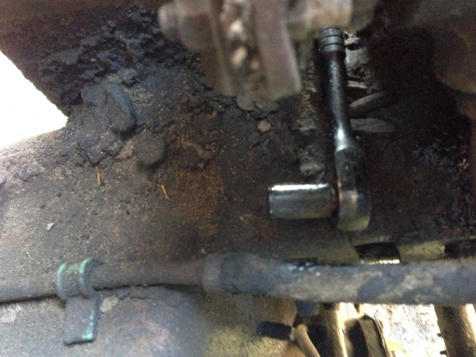 Wrench on bolt on greasy underside of vehicle