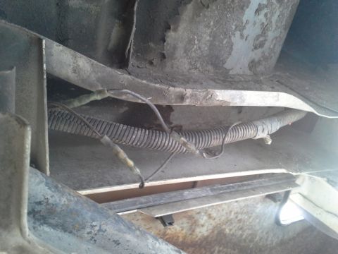 1991 Ford F-250 - The underside of a vehicle shows a bundle of wires protected by corrugated tubing, with some exposed connections.