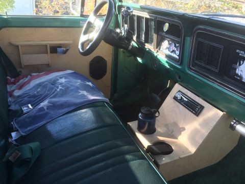1977 Ford F-350 - The interior of a 1977 Ford F-350 shows green vinyl seats, wood paneling, and the dashboard with gauges.